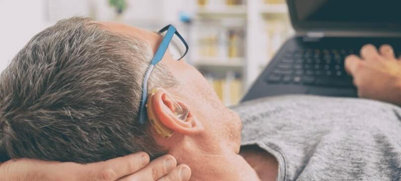 Man with a hearing aid using laptop