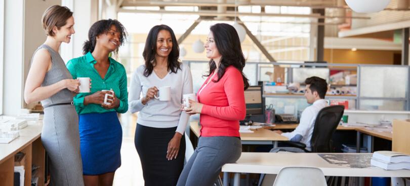 Group of female co-workers happily talking during coffee break at their workplace